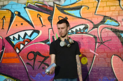 Full length of young man standing against graffiti wall