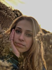 Close-up portrait of a young woman against sky