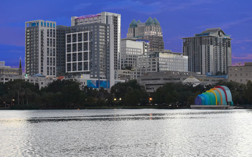 Modern buildings by river against sky in city