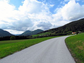 Country road against cloudy sky