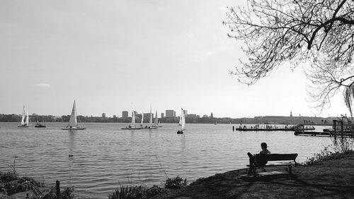 People sitting on sailboats by sea against sky