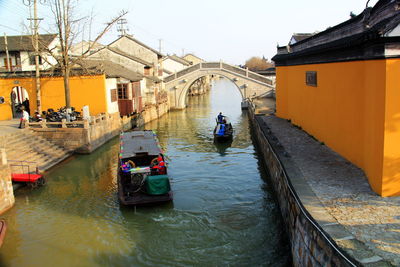 High angle view of boats in canal amidst buildings against sky