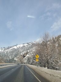 Road amidst trees against sky during winter