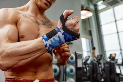 Muscular man wearing straps in gym
