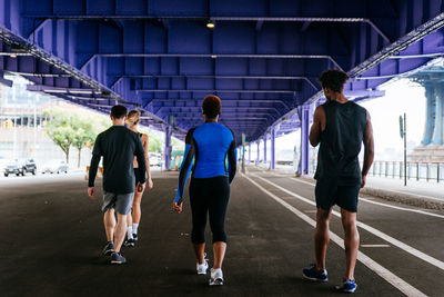 Rear view of people walking on bridge in city