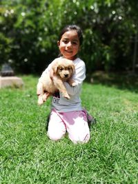 Portrait of young woman with dog on field