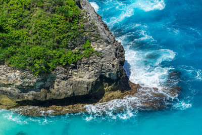 Vertiginous, swirling foamy water waves at the ocean photographed from above cliff.