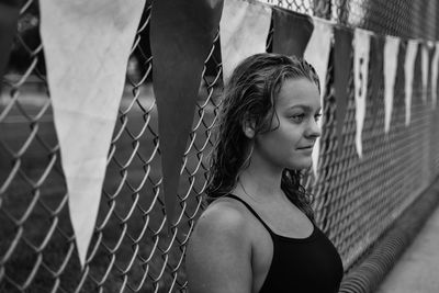 Young woman in swimwear by chainlink fence