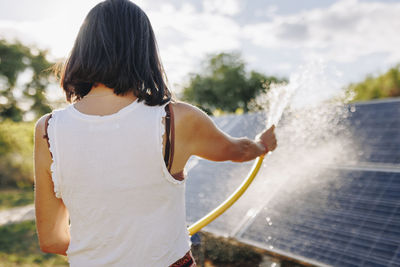 Woman cleaning solar panels in backyard