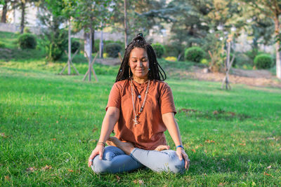 Young woman is sitting in the lotus position and meditating in a park. concept of healthy lifestyle.