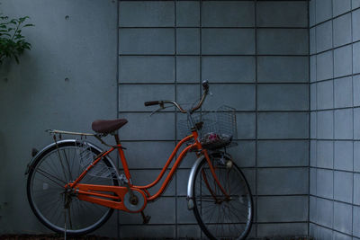 An orange bicycle was placed next to the fence
