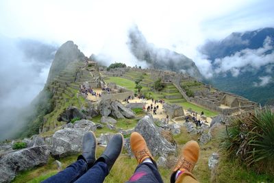 Low section of people on mountain against sky