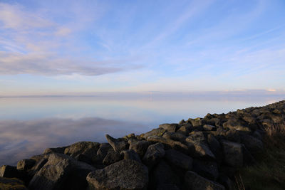Rocks by sea against sky during sunset