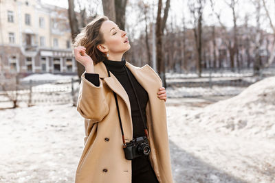 Young woman looking away while standing in winter