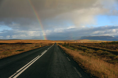 Road on landscape against rainbow in sky