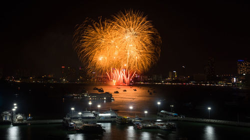 Firework display in city against sky at night