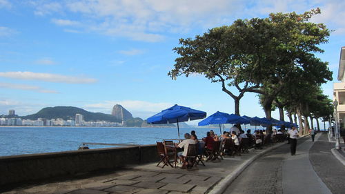 People at cafe by sea against sky