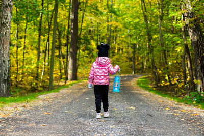 A girl is walking along a road in the forest with kerosene lamp