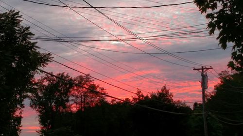 Low angle view of electricity pylon against cloudy sky