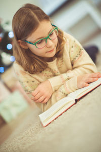 Girl reading book while lying at home during christmas