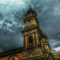 Low angle view of clock tower against cloudy sky