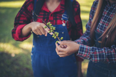 Midsection of women holding fruit