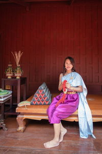 Portrait of smiling woman wearing traditional clothing sitting on wood