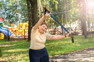 Happy woman holding umbrella against trees