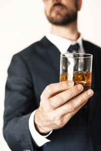 Midsection of man drinking glass against white background