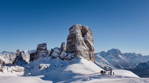 People on snowcapped mountain against blue sky