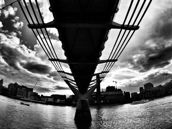 Low angle view of bridge over river against cloudy sky