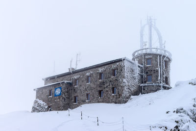 Low angle view of frozen built structure against sky