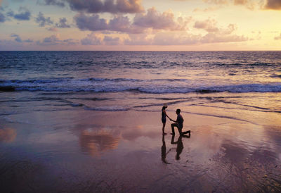 Man at beach against sky during sunset