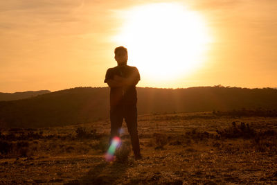 Man standing on field against sky during sunset
