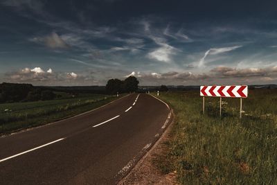 Road amidst field against sky