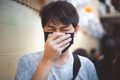 Close-up of man wearing mask coughing outdoors