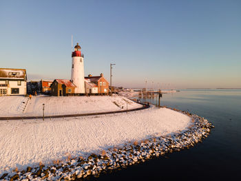 Lighthouse by sea against clear sky