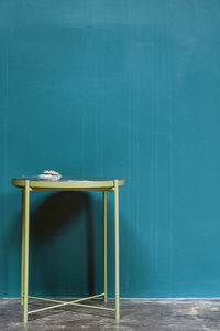 Close-up of empty blue table against wall