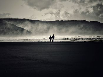 Silhouette people on beach against sky