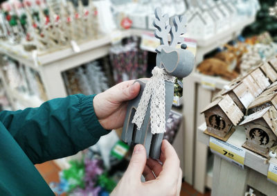 Cropped hand of young man holding christmas decoration at store