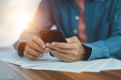 Midsection of man using mobile phone