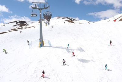 People skiing on snowcapped mountain against sky