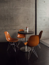 Empty chairs and table against wall