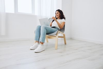 Full length of woman exercising on hardwood floor at home