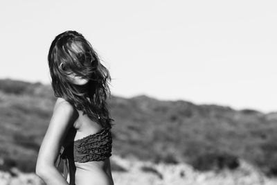 Midsection of woman standing on land against clear sky