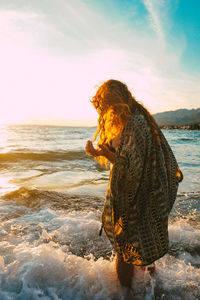 Woman standing on beach against sky during sunset