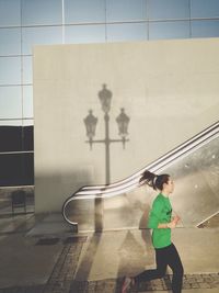 Side view of woman standing against wall