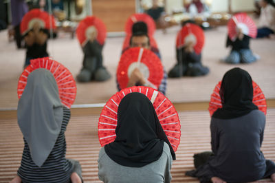 Dancers holding hand fans while sitting in studio