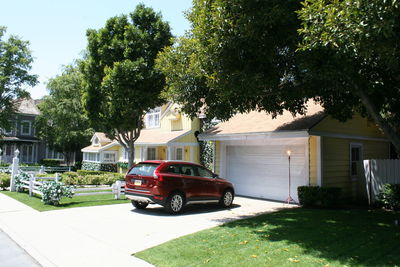 Cars on house by trees against sky