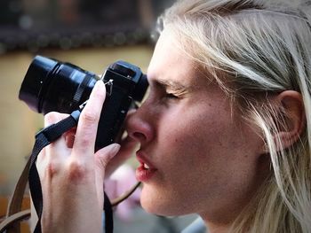 Close-up side view of young woman photographing with camera